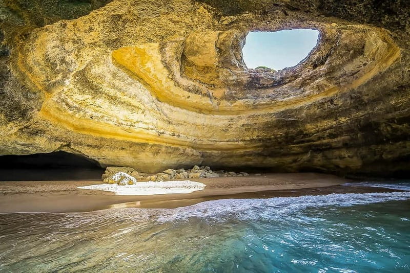 A small boat under the sea arch at Benagil, on the Algarve coast